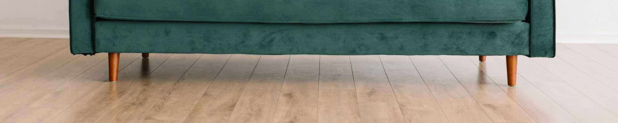 Laminate floor with a green velvet sofa