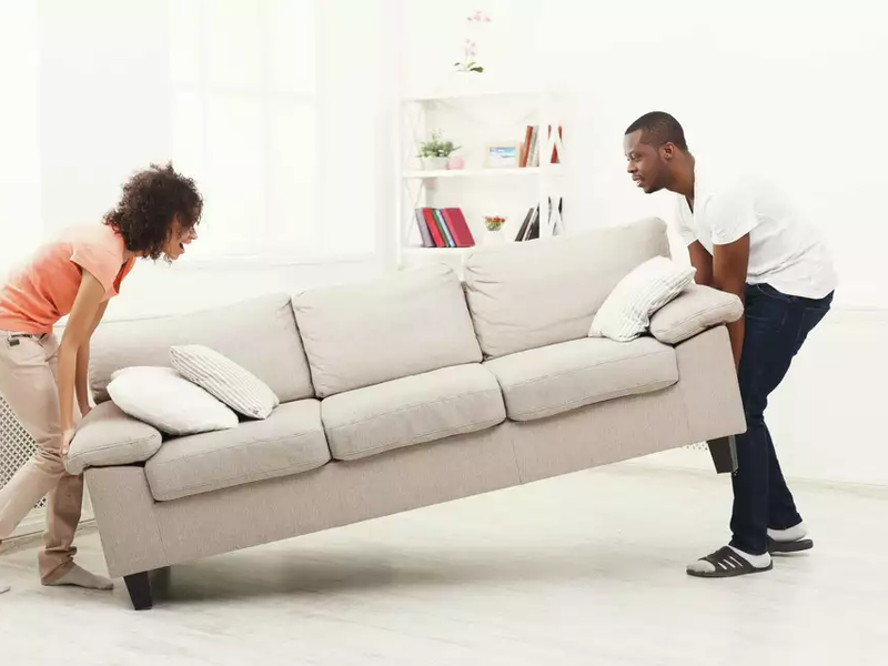 Couple moving furniture to prepare for carpet installation